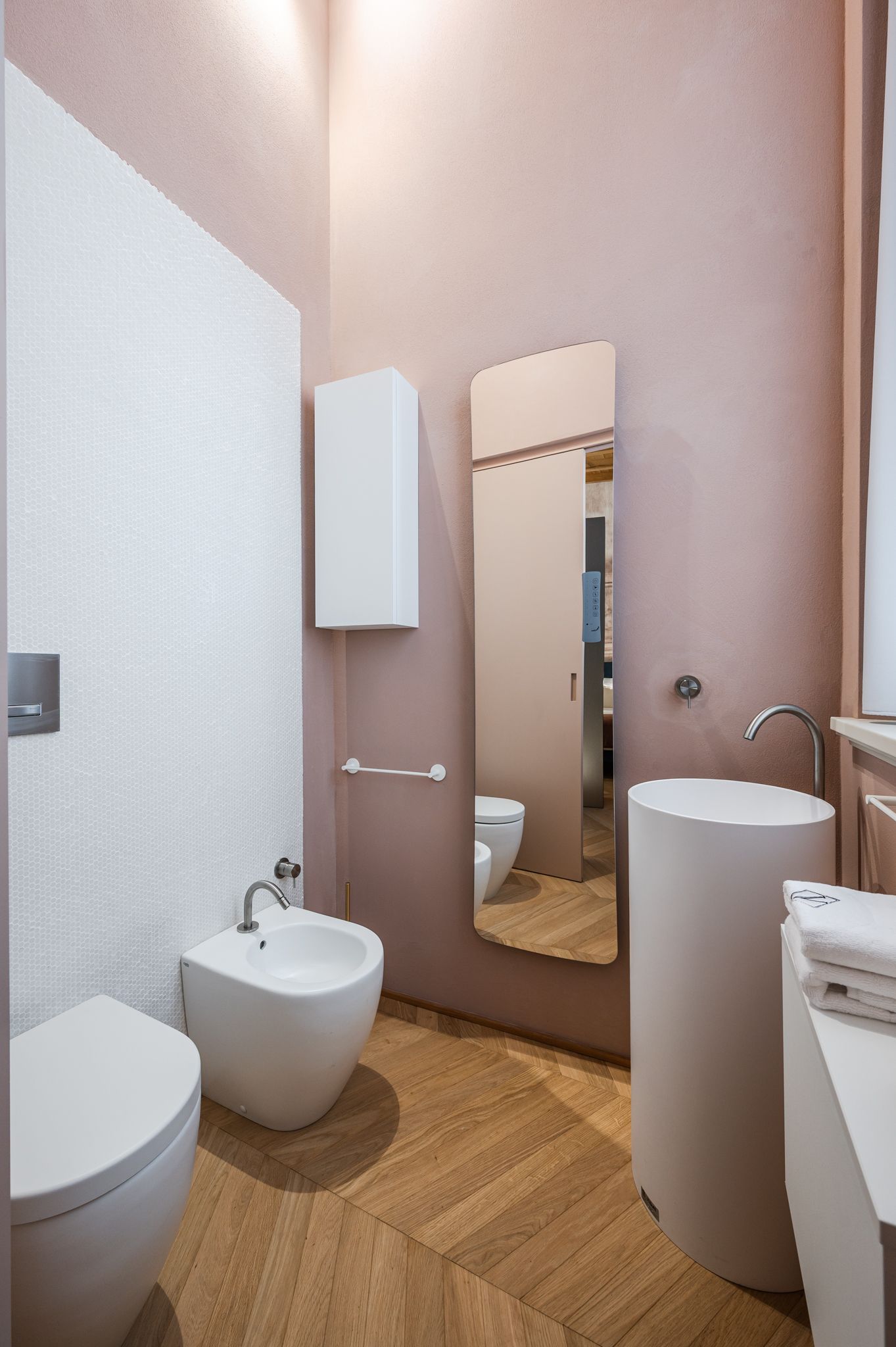 Bagno rosa con lavabo tondo freestanding e specchio verticale